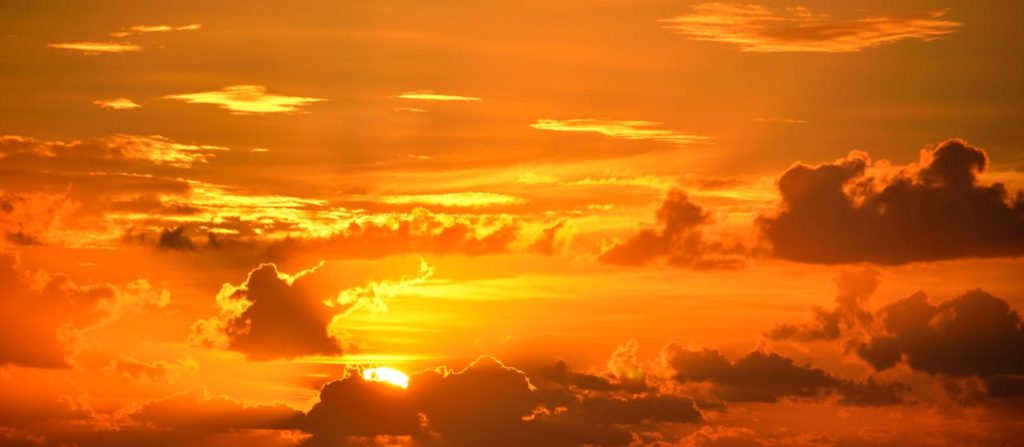 Orange sunset with clouds scattered across the sky, creating a warm and peaceful atmosphere that seems to soothe the senses and regulate circadian rhythm